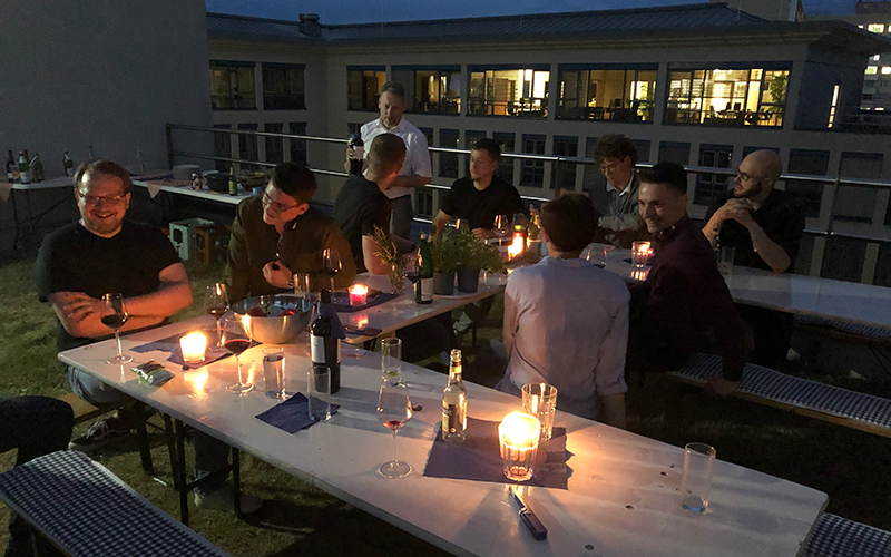 Studenten und Kollegen der ADVITEC sitzen bei einem guten Wein auf Dachterasse zum Tag des Neworkings